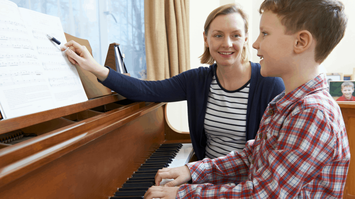 Piano teacher teaching a boy to play piano.