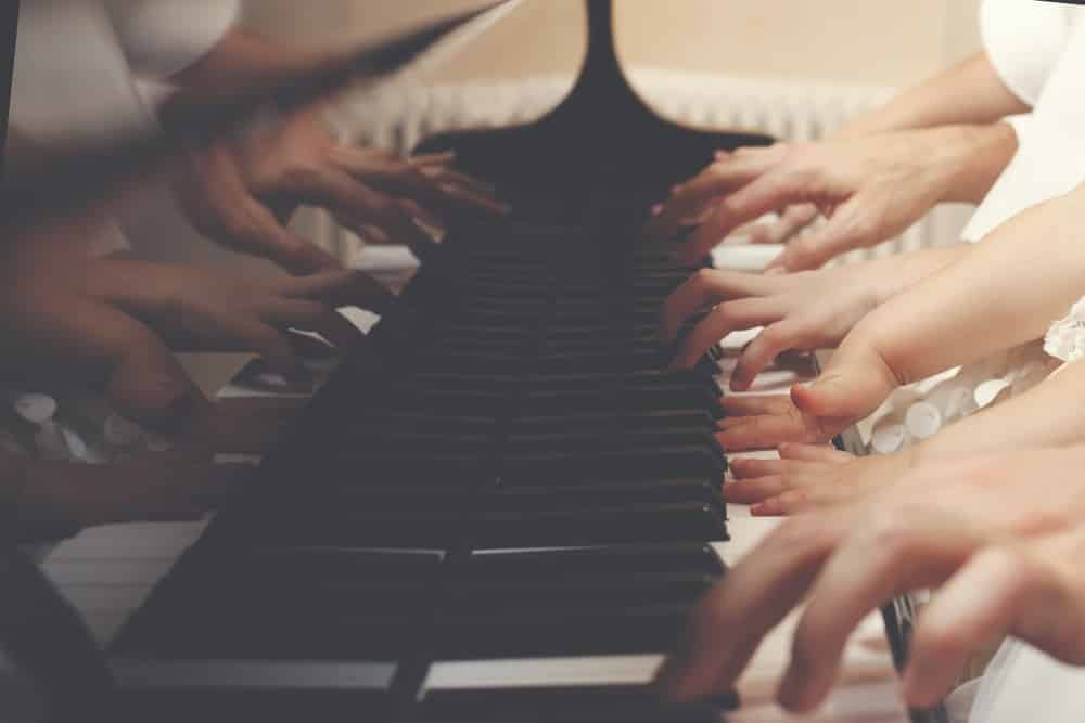 Many hands playing the piano.