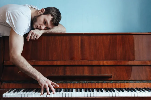 Frustrated man struggling with piano practice, highlighting common mistakes that slow piano skill improvement