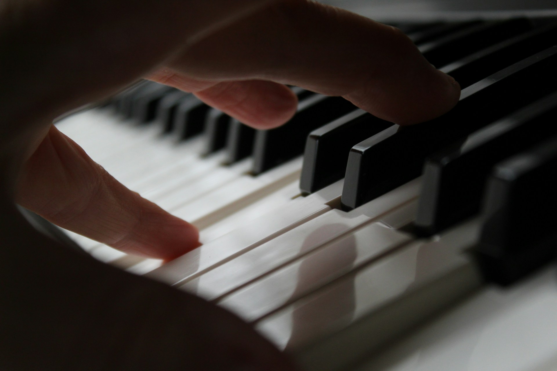 Close up of hand pressing piano keys, fingers curved over black and white keys