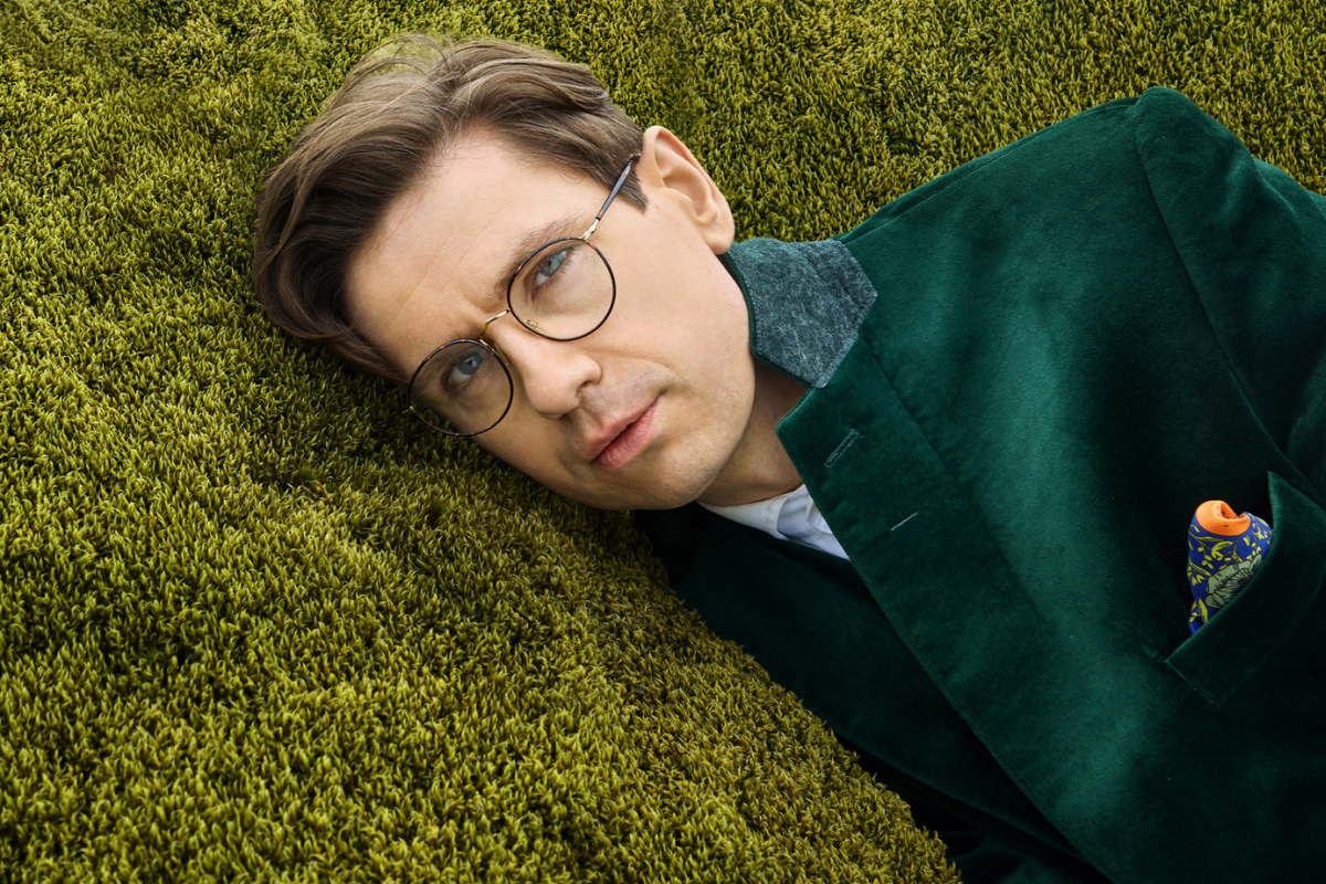 Man with glasses reclining on textured green surface