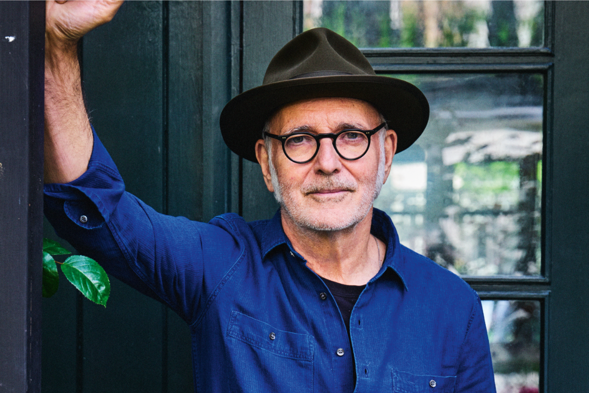 Man wearing hat and glasses standing beside doorway