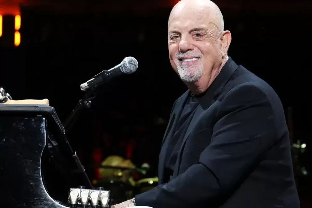 Smiling bald musician seated beside microphone and piano