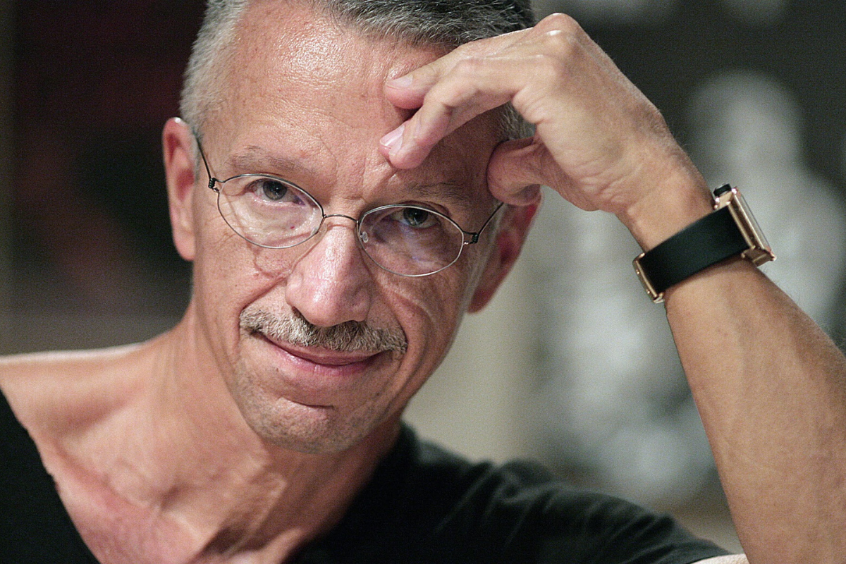 Man with glasses resting head thoughtfully on hand