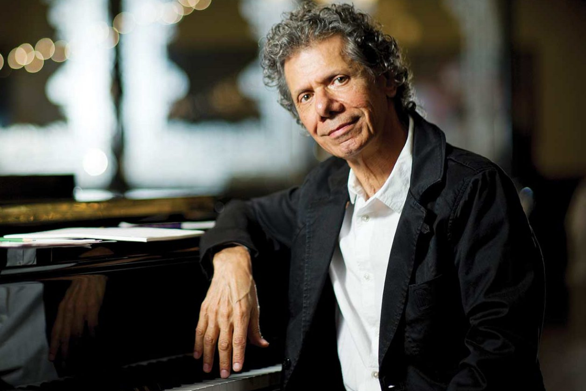 Curly-haired pianist posing beside grand piano indoors