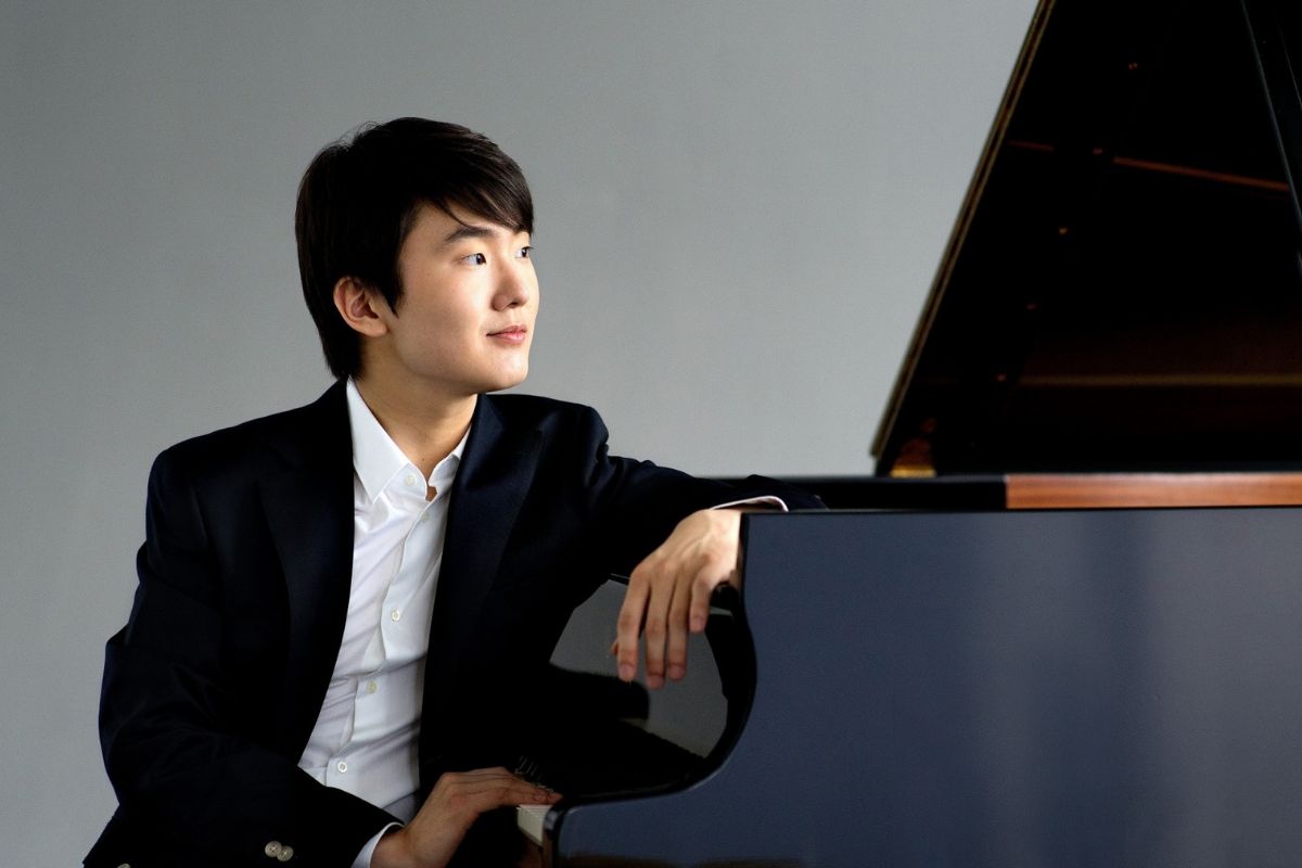 Young pianist sitting beside grand piano thoughtfully