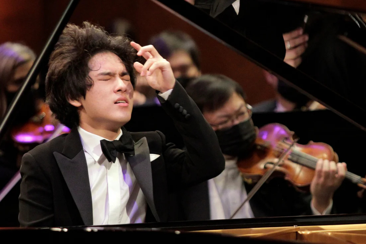 Young pianist performing passionately with orchestra behind him