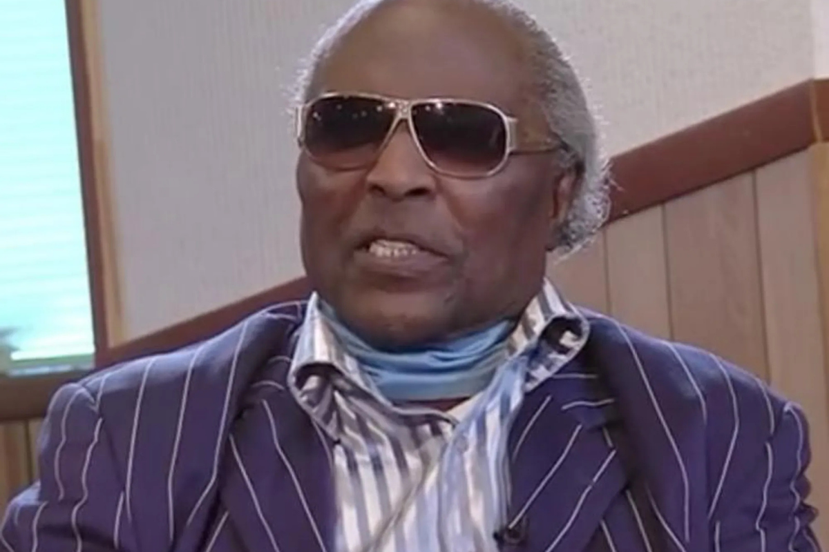 Man wearing sunglasses and striped suit during interview indoors
