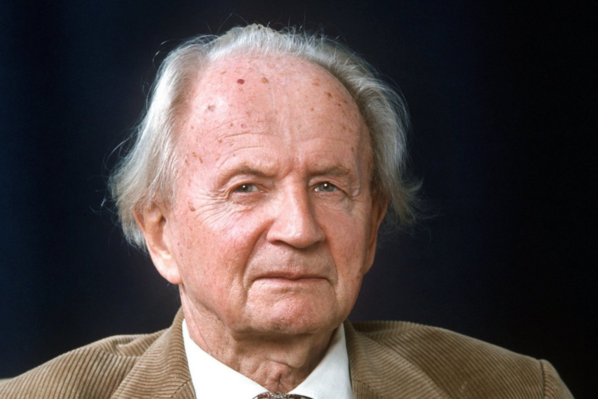 Elderly white-haired man wearing jacket against dark background