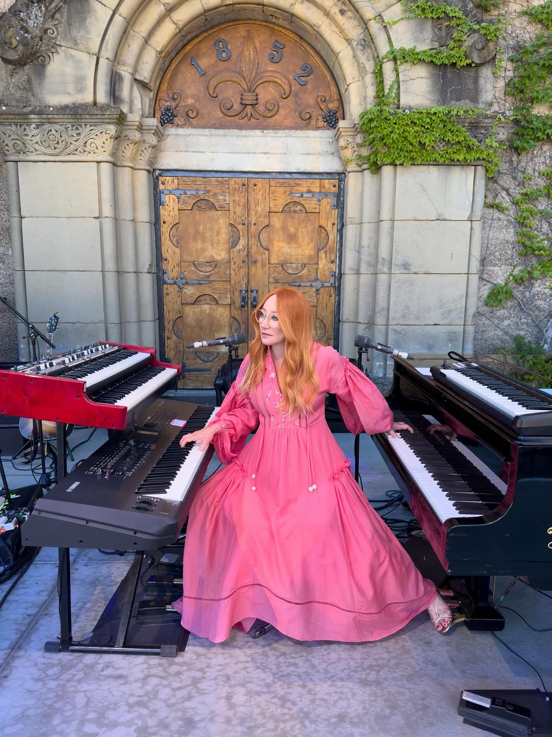 Tori Amos performing live, known for her powerful piano technique, expressive stage presence, and constantly evolving interpretations of her music.