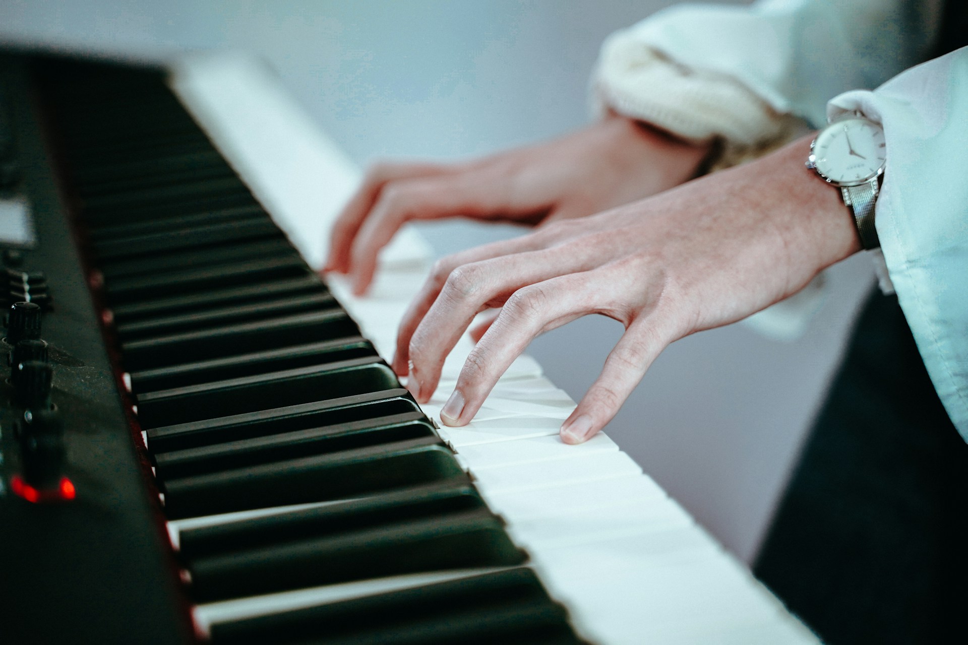 Person playing digital piano, hands on keys with wristwatch visible