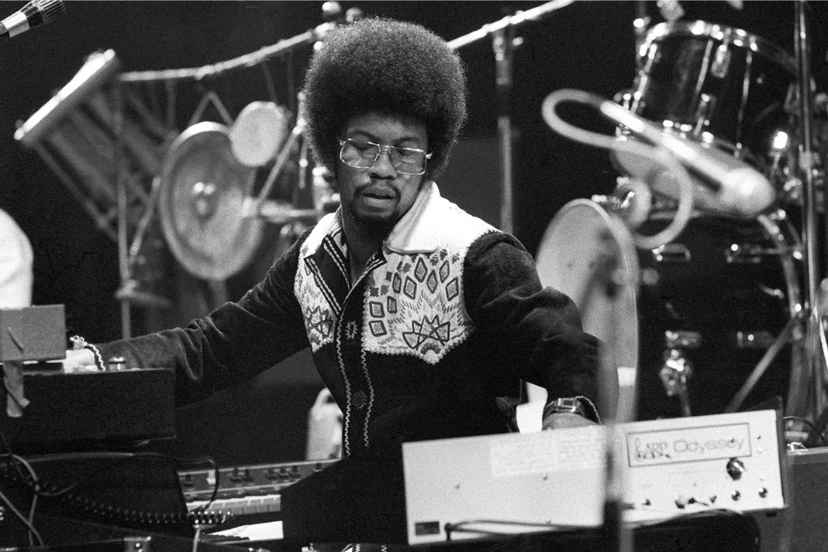 Musician performing onstage beside keyboards and percussion instruments