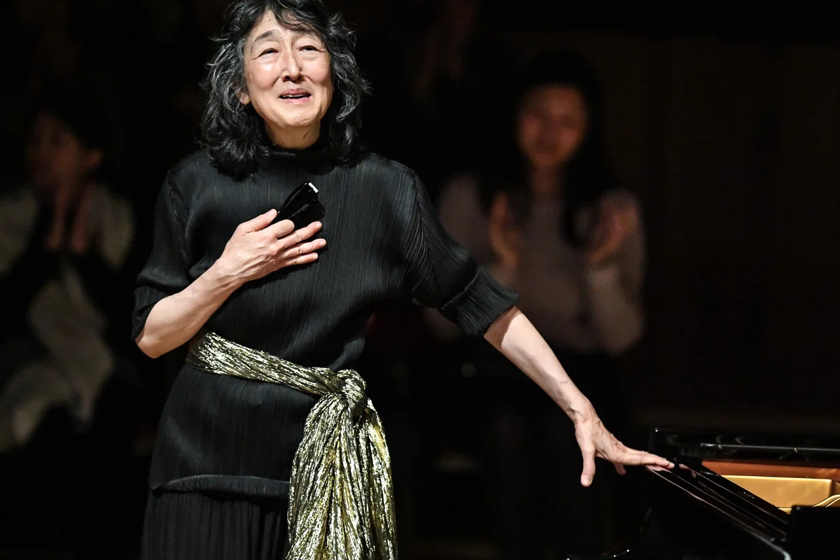 Woman acknowledging audience beside concert grand piano