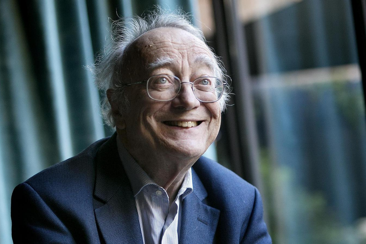 Smiling elderly man wearing glasses beside large windows