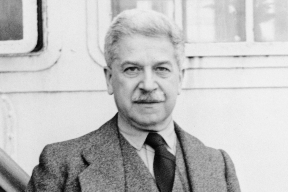 Gray-haired man in suit posing beside building exterior