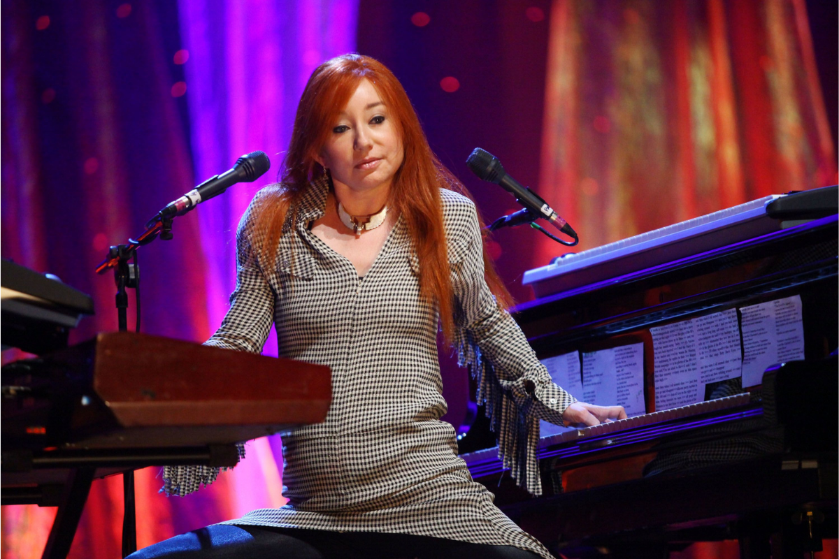 Red-haired musician seated between microphones and keyboard instruments