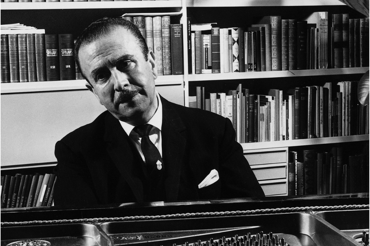 Man seated at piano before bookshelves in study